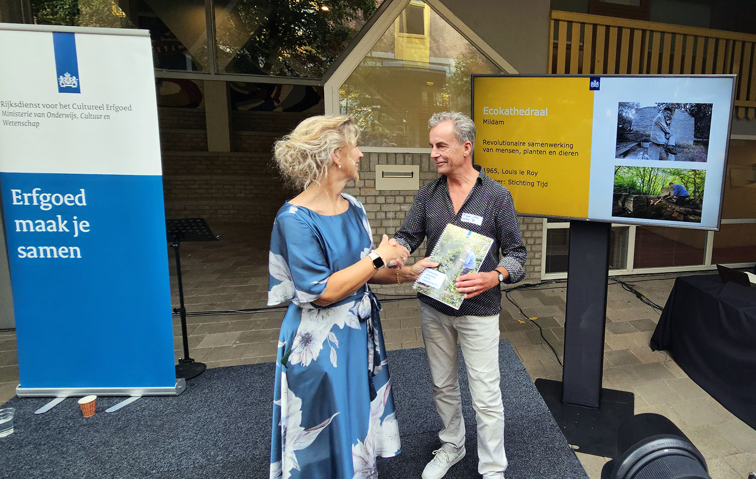Bouwmeester Marcel Prins van de ecokathedraal Mildam krijgt de papieren rond de aanwijzing tot Rijksmonument uit handen van algemeen directeur Susan Lammers van de Rijksdienst voor het Cultureel Ergoed. (foto: Peter Wouda)