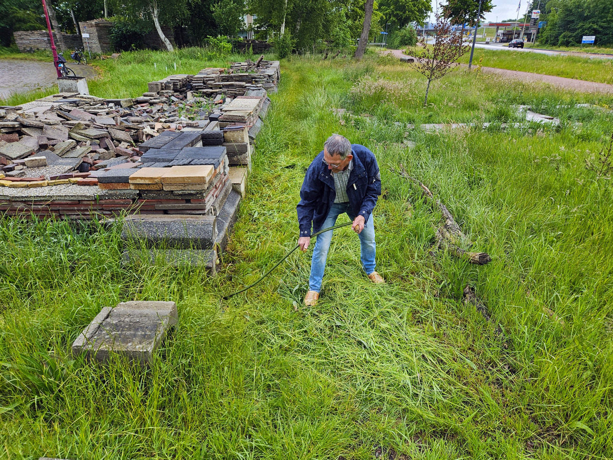 Johannes Zijlstra maait het gras dat op het pad groeit in de Le Roy-tuin met de zeis 